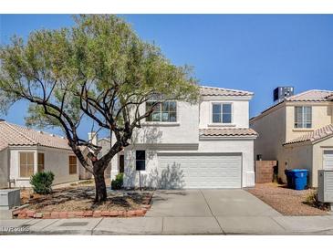 Charming two-story home features a well-manicured front yard and a classic stucco facade, creating a welcoming curb appeal at 1716 Klamath Falls Way, Las Vegas, NV 89128
