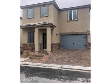 Two-story home with tan stucco, stone accents, a two-car garage, and a paver driveway and walkway at 5414 Enchanted Rose St, Las Vegas, NV 89148
