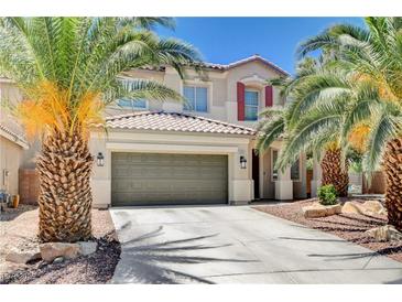 Charming two-story home with a tile roof, desert landscaping, and palm trees framing the front entrance and two-car garage at 6569 Cedar Waxwing St, North Las Vegas, NV 89084