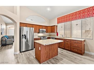 Well-lit kitchen with stainless steel refrigerator and kitchen island topped with granite countertops at 9733 Northern Dancer Dr, Las Vegas, NV 89117