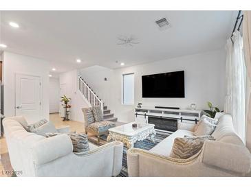 Bright living room features plush seating, modern entertainment center with fireplace, and staircase at 10347 Restless River St, Las Vegas, NV 89141