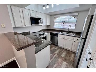 Well-lit kitchen featuring stainless steel appliances, granite countertops, and modern white cabinetry at 8455 W Sahara Ave # 213, Las Vegas, NV 89117