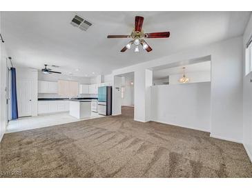 View of open-concept living room with a ceiling fan that connects to the kitchen with white cabinets at 8529 Gold Flash Ave, Las Vegas, NV 89129