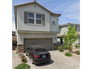 Two-story home featuring a two-car garage, stone accents, a tiled roof, and a paved driveway with nice landscaping at 10163 Kings Amethyst St, Las Vegas, NV 89141