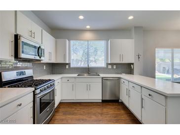 Bright kitchen features stainless steel appliances, white cabinetry and counters, and a modern backsplash at 1013 Corsica Ln, Las Vegas, NV 89144