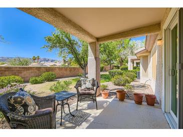 Relaxing covered patio with comfortable seating, potted plants, and a view of the landscaped backyard at 2085 Joy View Ln, Henderson, NV 89012