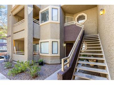 Condo with a private entrance, stairway, and a small landscaped area with shrubbery in front of the building at 5052 S Rainbow Blvd # 201, Las Vegas, NV 89118