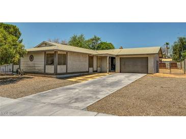 Single-story home with stucco exterior, two-car garage, gravel landscaping and long concrete driveway at 671 Riata Way, Las Vegas, NV 89110