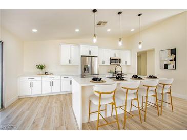 Modern kitchen featuring white cabinetry, stainless steel appliances, a quartz countertop island, and stylish pendant lighting at 1006 Blue Lantern Dr, Henderson, NV 89015