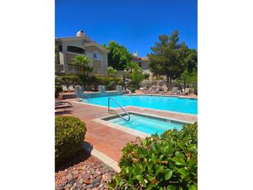 A luxurious pool is surrounded by lounge chairs, mature trees, and a building at 1500 Cardinal Peak Ln # 201, Las Vegas, NV 89144