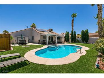 Inviting backyard with a sparkling blue pool, green grass, and covered patio perfect for relaxation at 5025 Chambliss Dr, Las Vegas, NV 89130