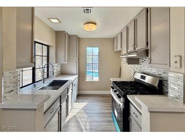 Well-lit kitchen features stainless steel appliances, modern cabinetry, mosaic tile backsplash, and bright quartz countertops at 4805 Nara Vista Way # 203, Las Vegas, NV 89103