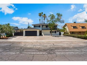 Two-story home with a black roof, black garage door, palm trees and desert landscaping in front at 2724 Natalie Ave, Las Vegas, NV 89121