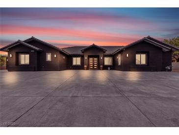 Elegant single-story home featuring a dark exterior, tile roof and a spacious concrete driveway at 6235 N Fort Apache Rd, Las Vegas, NV 89149