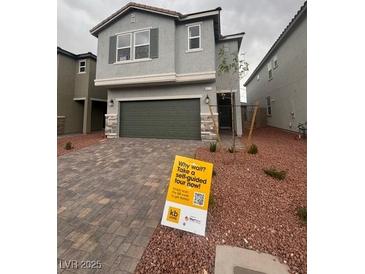 Two-story home featuring gray stucco, stone accents, a two-car garage, and drought-resistant landscaping at 6604 Bowery St, Las Vegas, NV 89148