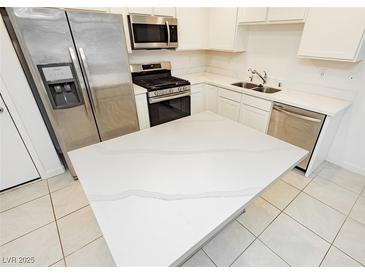 Bright kitchen features stainless steel appliances, white cabinetry, a large island, and tile flooring at 675 Omaggio Pl, Henderson, NV 89011