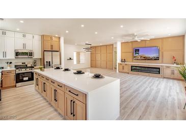 Open kitchen and living area featuring a large island, modern appliances, and hardwood flooring at 2561 Terrytown Ave, Henderson, NV 89052