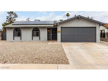 Charming single-story home with gray stucco, gravel landscaping, solar panels, and attached two-car garage at 4416 Rip Van Winkle Ln, Las Vegas, NV 89102