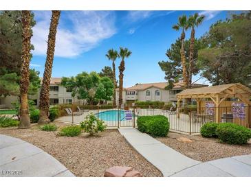 Community pool area with desert landscaping, tall palm trees, and pergola covered seating at 2627 S Durango Dr # 201, Las Vegas, NV 89117