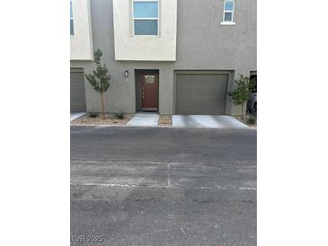 Neutral-toned townhome featuring a garage, front door, and minimalist landscaping at 2755 Atomic Tangerine Way # 2, Las Vegas, NV 89183