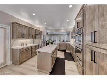 Spacious kitchen features wood cabinets, stainless steel appliances and center island with white countertop at 3001 Walnut Park Ct, Henderson, NV 89052