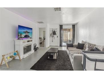 Bright living room featuring a fireplace, a large sofa, and sliding glass doors to the patio at 3008 Saint George St # F, North Las Vegas, NV 89030
