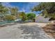Long driveway leading to a two-car garage, surrounded by mature trees and a fenced yard at 6990 W Richmar Ave, Las Vegas, NV 89178