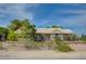 Charming single-story home with a tiled roof, complemented by a lush green landscape and a clear blue sky at 6990 W Richmar Ave, Las Vegas, NV 89178