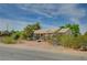 A charming single-story house with a tile roof, set against a backdrop of clear blue skies and lush greenery at 6990 W Richmar Ave, Las Vegas, NV 89178