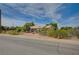 A cozy single-story house, surrounded by trees and brush, sits under a bright blue sky at 6990 W Richmar Ave, Las Vegas, NV 89178