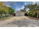 Front view of a two-car garage with a wide driveway, framed by trees and a fenced perimeter at 6990 W Richmar Ave, Las Vegas, NV 89178
