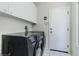 Bright laundry room with modern washer and dryer and overhead cabinet storage at 79 Emerald Dunes Cir, Henderson, NV 89052