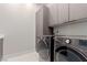 Modern laundry room featuring gray cabinets, sleek washer and dryer, and tiled floors at 7062 Maverick St, Las Vegas, NV 89131