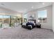 Bright main bedroom featuring neutral carpet, sitting area, large windows, and sliding glass door to the back yard at 7062 Maverick St, Las Vegas, NV 89131