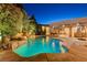 Backyard pool area at dusk with waterfall feature, mature landscaping, and ample patio space at 8275 W Craig Rd, Las Vegas, NV 89129