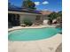 Inviting kidney shaped pool surrounded by a concrete patio, plants and solar panels above at 611 E Fairway Rd, Henderson, NV 89015
