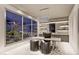 Bright home office with a modern desk, stylish chairs, built-in shelves, and large windows overlooking a serene garden at 616 Scenic Rim Dr, Henderson, NV 89012