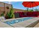 Blue glass fire pit with red patio furniture and umbrella at 3870 Valles Caldera Ct, Las Vegas, NV 89118