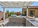 Outdoor kitchen with grill, sink and granite countertop under pergola at 3870 Valles Caldera Ct, Las Vegas, NV 89118