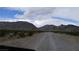 Dirt road leads to a desert property with mountain views and native vegetation under a cloudy sky at , Pahrump, NV 89060