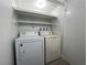 Functional laundry area features white appliances and shelving for optimal organization and storage at 4281 White Sands Ave, Las Vegas, NV 89121