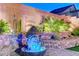 Relaxing backyard fountain feature with lush desert landscaping and ambient lighting at 10407 Restless River St, Las Vegas, NV 89141