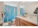 Bright bathroom with dual sinks, quartz countertops and turquoise curtains at 10407 Restless River St, Las Vegas, NV 89141