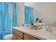 Bright bathroom with dual sinks, quartz countertops and turquoise curtains at 10407 Restless River St, Las Vegas, NV 89141