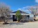 A single story home with gravel landscaping and a white porch in a sunny environment at 1130 N Leslie St, Pahrump, NV 89060