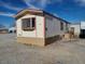 A manufactured home with beige siding and trim sitting on a lot of gravel at 1130 N Leslie St, Pahrump, NV 89060
