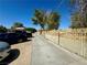 Wide driveway leading to a property with a secure fence and trees in the background at 3895 Mountain Trl, Las Vegas, NV 89108