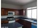 A kitchen with brown cabinets, white appliances, and a double basin sink under the window at 4085 Oliver Sagebrush Dr, Las Vegas, NV 89122
