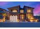 Modern home with stone accents and a three-car garage at dusk at 10632 Patina Hills Ct, Las Vegas, NV 89135