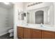Bathroom with double vanity, wood cabinets, large mirror, and combination tub and shower at 9333 Leaping Deer Pl # 102, Las Vegas, NV 89178